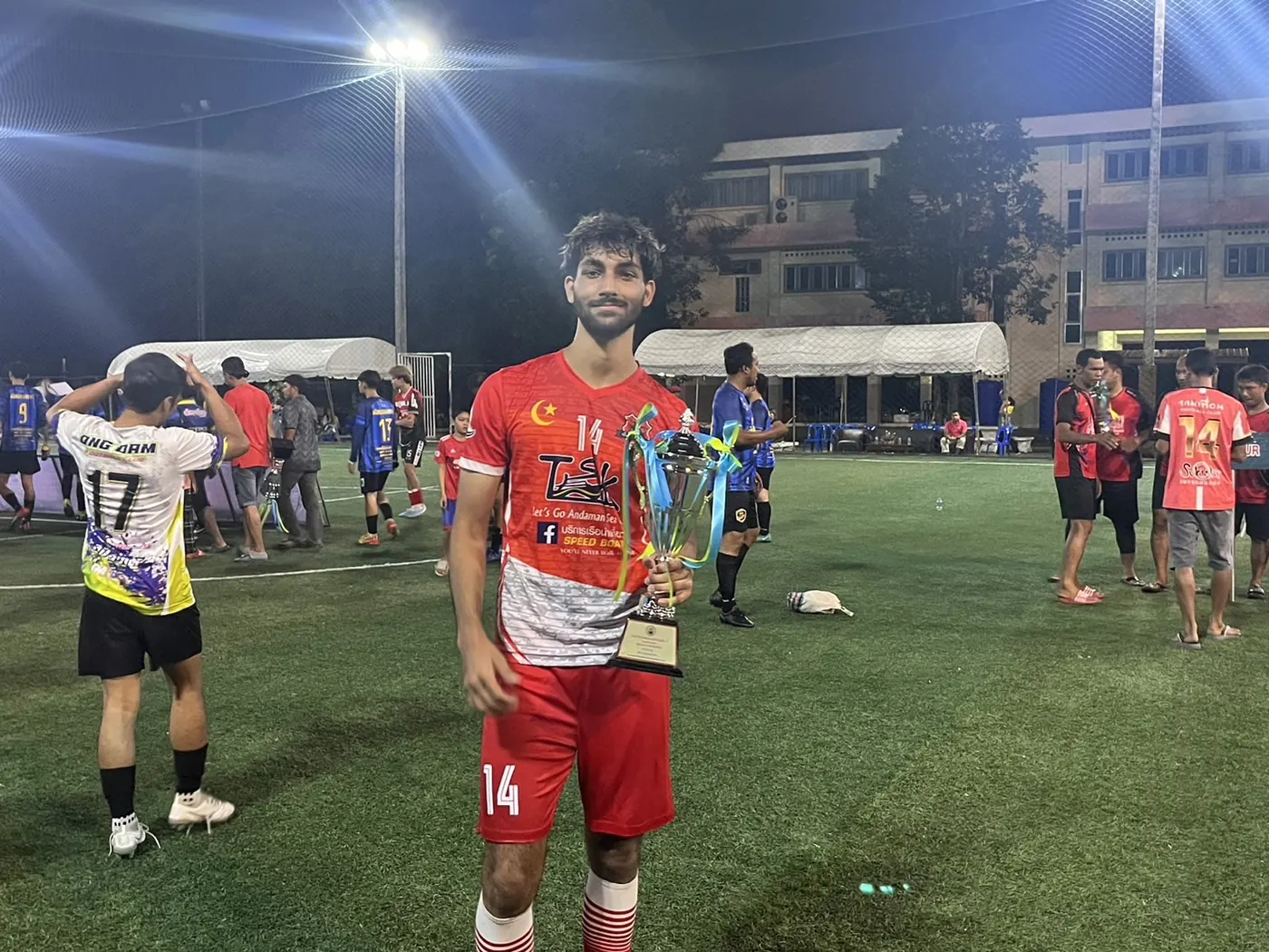 With a trophy on the pitch at night